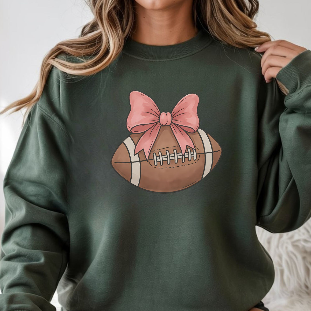 Coquette football graphic featuring a brown football topped with a pink bow in a feminine sports design