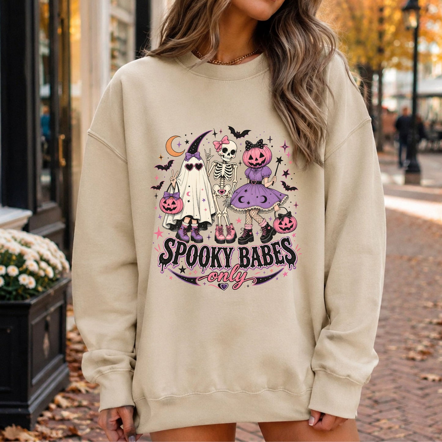 Spooky Babes Only Halloween DTF transfer featuring three fashionable spooky characters, including a sheet ghost in a witch hat and heart sunglasses, a bow-wearing skeleton and a pumpkin-headed witch in a purple dress, surrounded by pink jack-o-lanterns, bats, stars and crescent moon accents on a cream sweatshirt mockup.