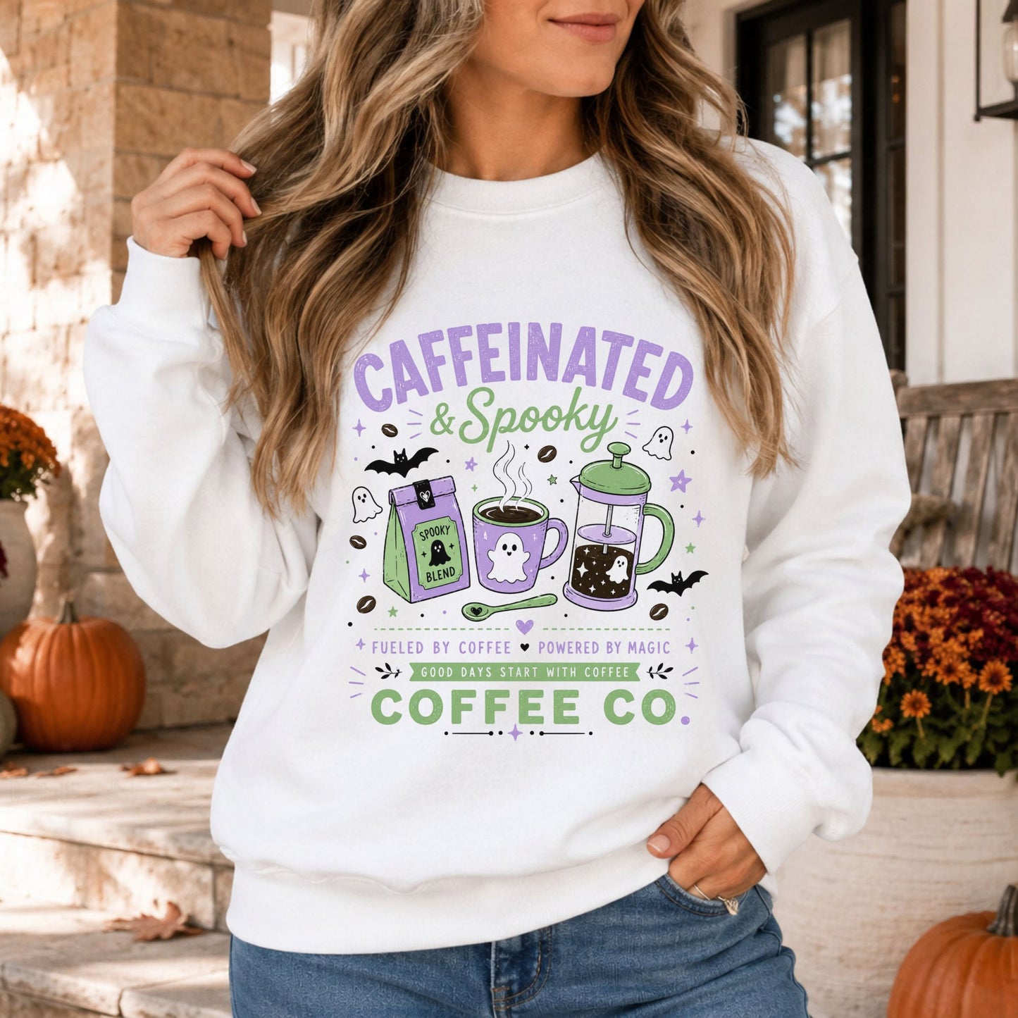Caffeinated and Spooky Halloween DTF transfer featuring a purple and green coffee bag, steaming ghost mug, French press, coffee beans, bats, stars and tiny ghosts on a white sweatshirt mockup.