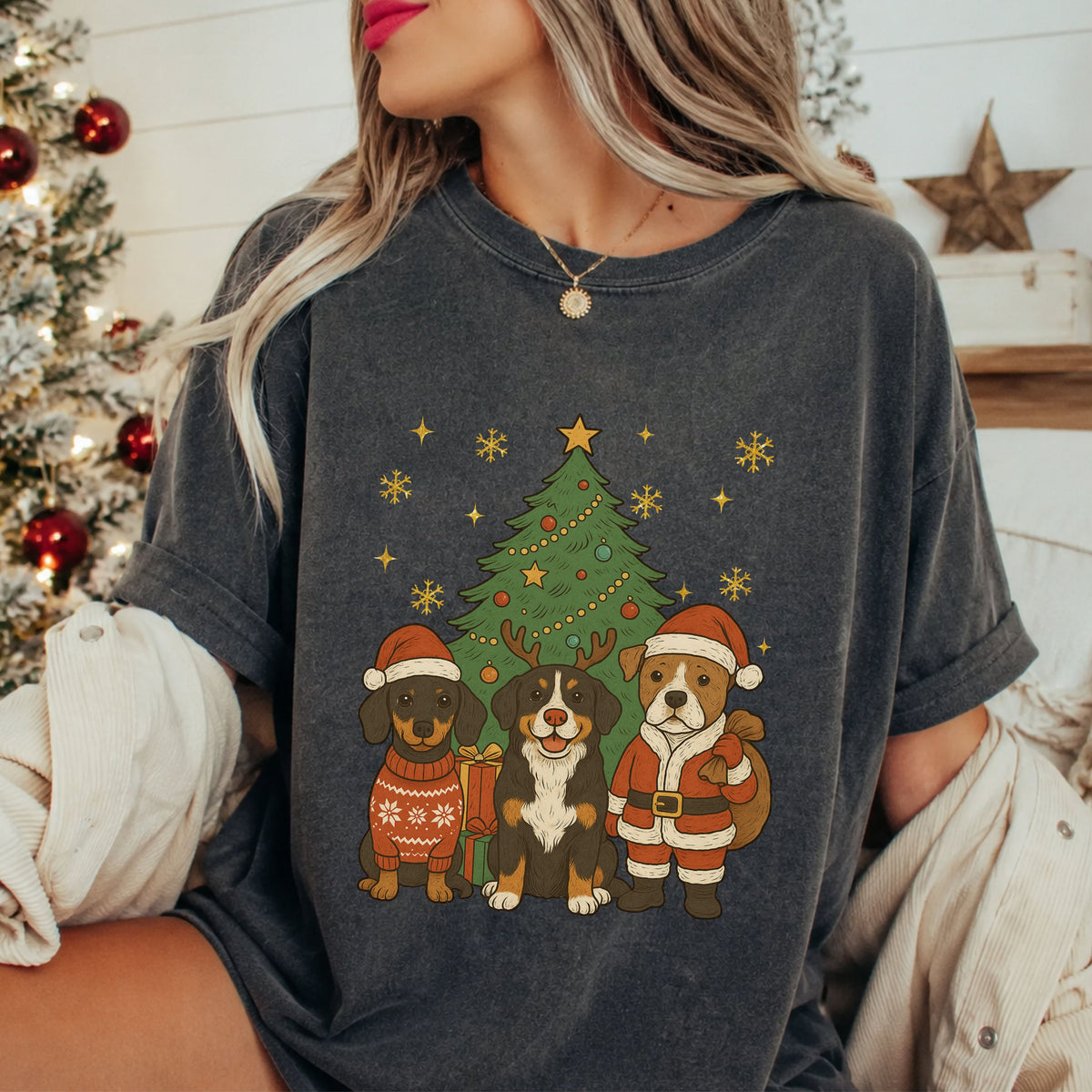 Three dogs beside a Christmas tree and gifts: one in a sweater and Santa hat, one with reindeer antlers, and one in a Santa suit holding a sack, with gold snowflakes.