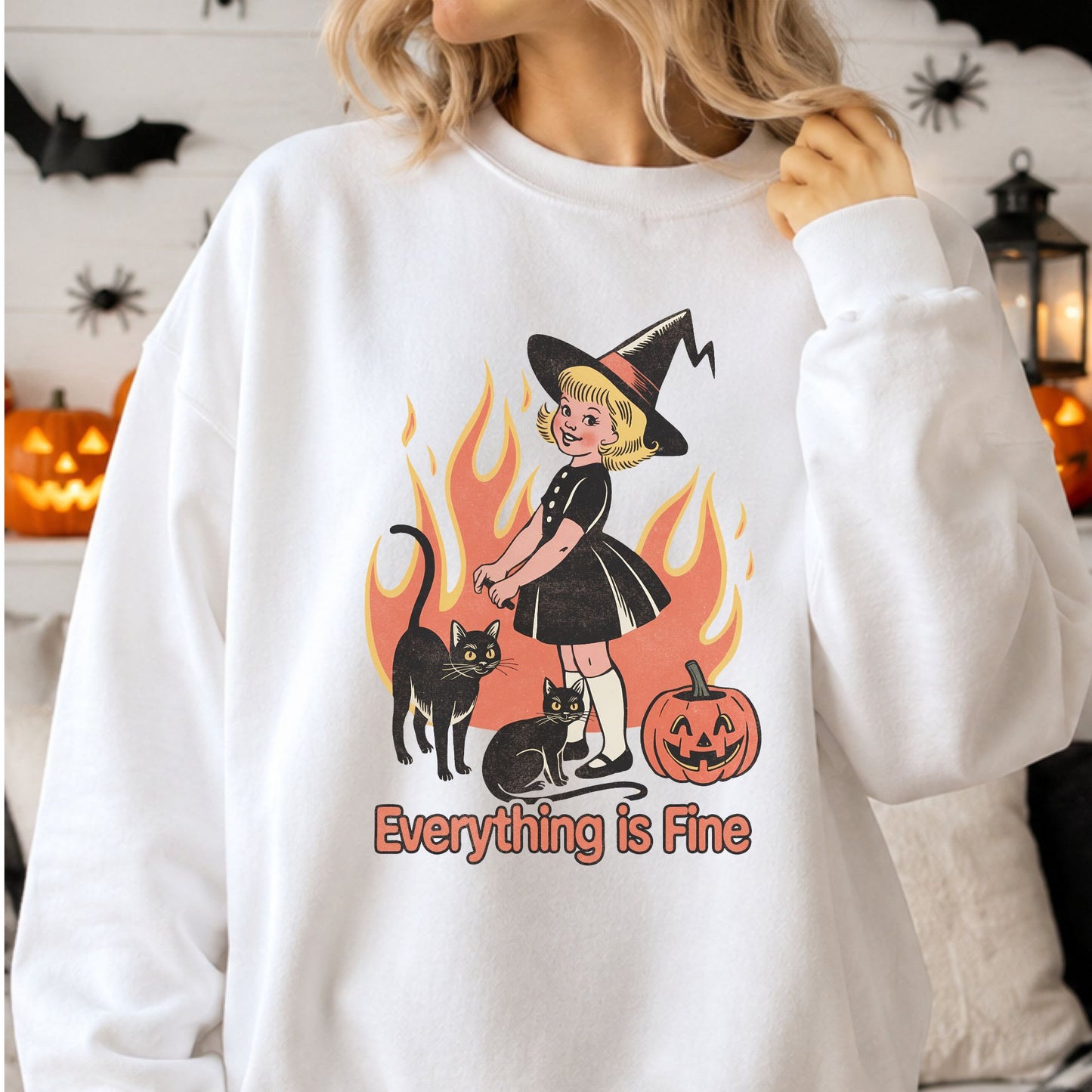Retro Halloween DTF transfer featuring a smiling witch girl standing with two black cats and a jack-o-lantern in front of orange flames with the phrase Everything Is Fine, displayed on a white sweatshirt mockup.