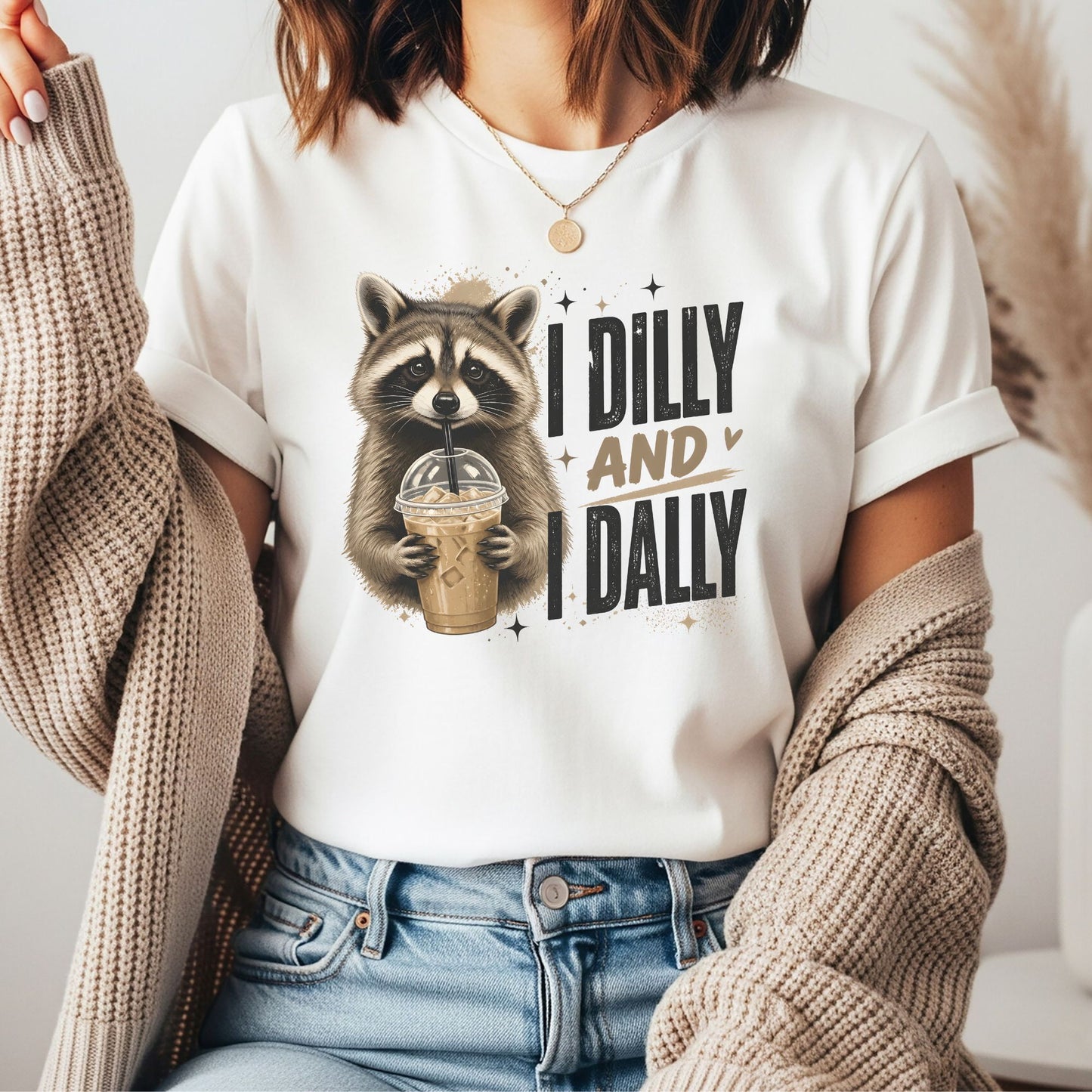 Funny raccoon holding iced coffee graphic with I Dilly And I Dally phrase, coffee lover shirt design, ADHD humor artwork, cute woodland animal graphic