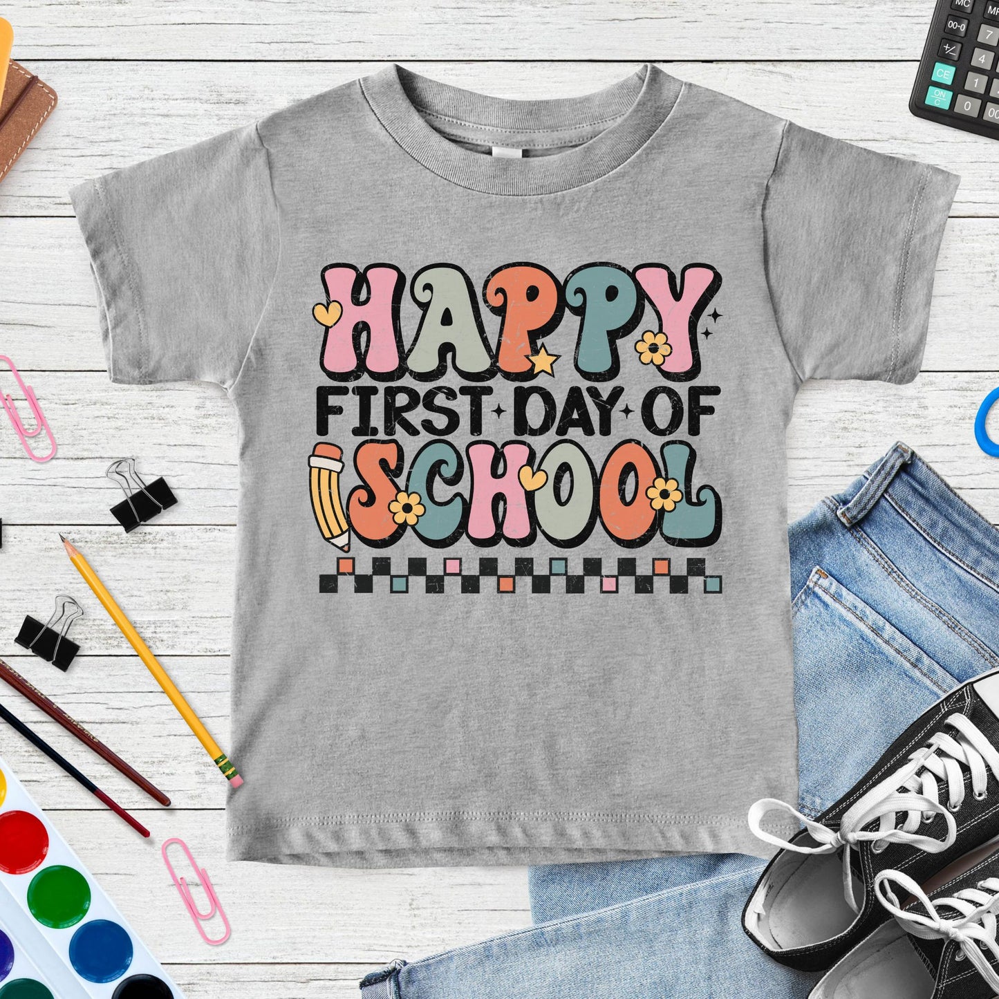 Happy First Day of School design featuring colorful retro lettering, a pencil, flowers, hearts, stars, and checkerboard accents for toddler, kids, and youth shirts.