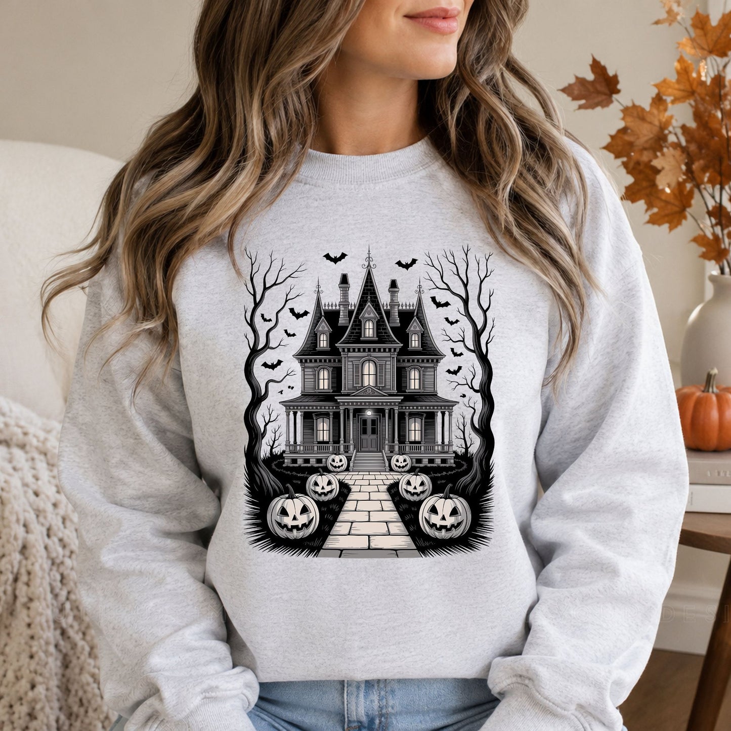 Black-and-white haunted house Halloween DTF transfer featuring a detailed Victorian gothic mansion, glowing windows, flying bats, twisted bare trees and a pathway lined with jack-o’-lantern pumpkins on a gray sweatshirt mockup.