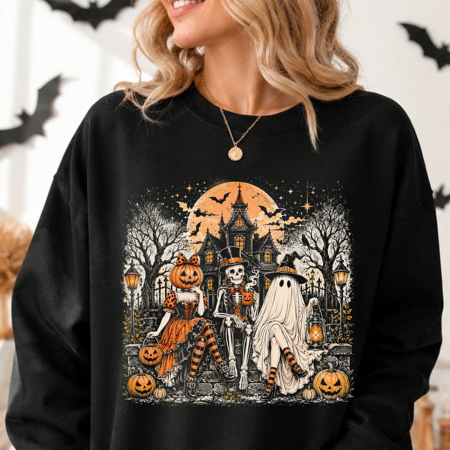 Detailed haunted mansion Halloween DTF transfer featuring a pumpkin-headed woman, top-hat skeleton and witchy sheet ghost seated beneath an orange full moon with jack-o-lanterns, bats, lanterns and a gothic Victorian house on a black sweatshirt mockup.