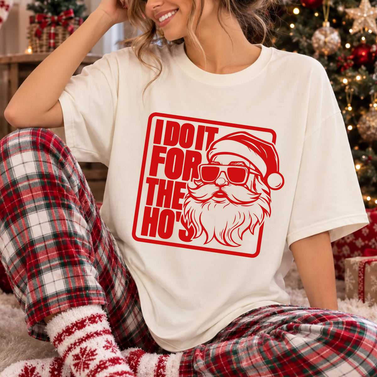 Red Santa wearing sunglasses beside bold “I Do It For The Ho's” lettering inside a rounded rectangular border, forming a funny Christmas DTF transfer design.