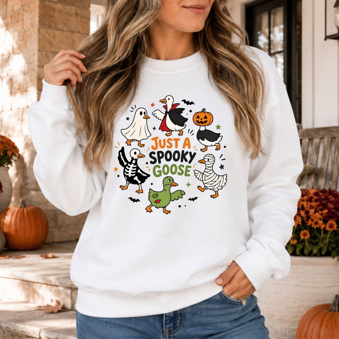Just a Spooky Goose Halloween DTF transfer featuring six playful geese dressed as a ghost, vampire, jack-o’-lantern, skeleton, mummy and zombie, surrounded by colorful stars and flying bats on a white sweatshirt mockup.