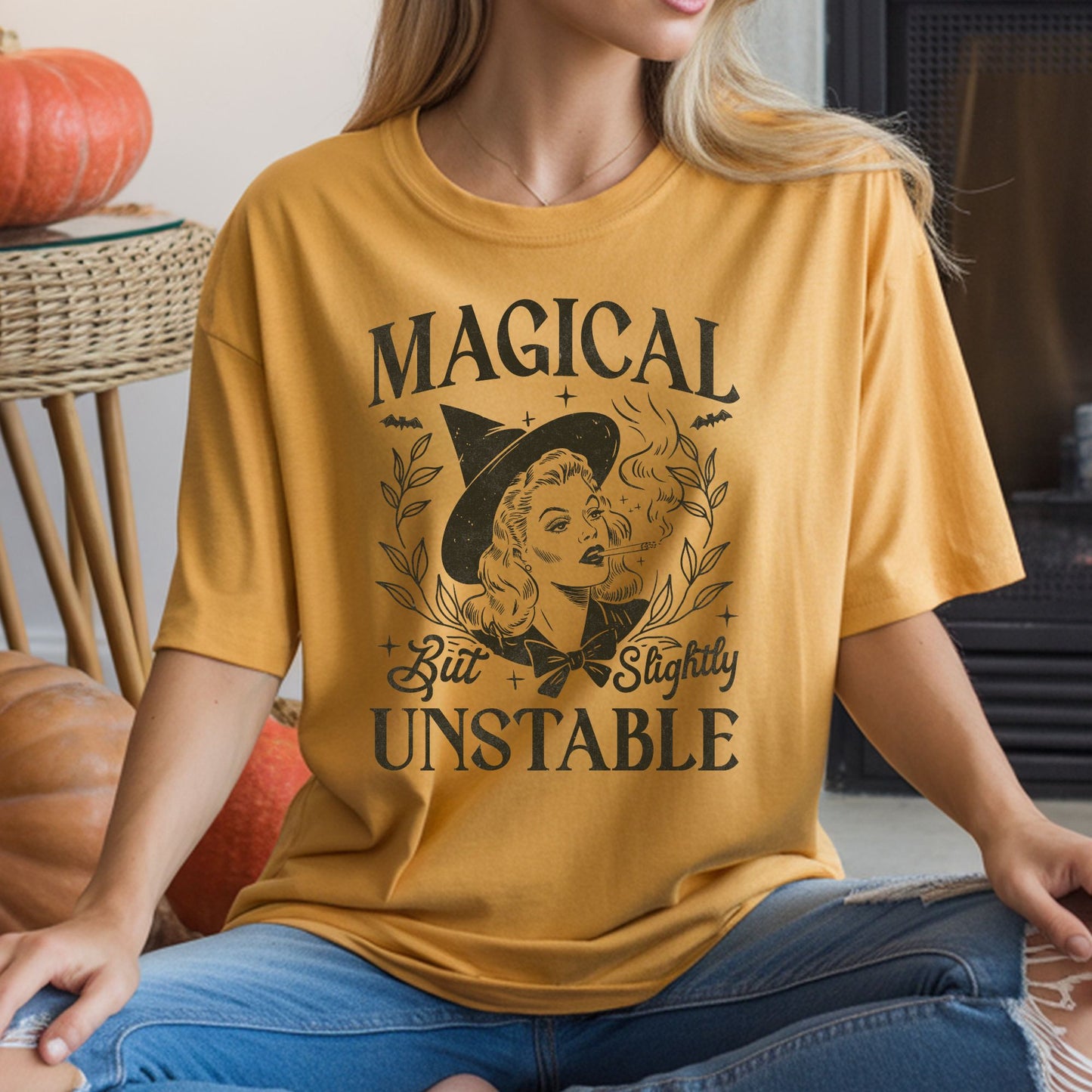 Vintage Magical but Slightly Unstable Halloween DTF transfer featuring a glamorous retro witch wearing a pointed hat and smoking, framed by leafy branches, bats, stars and distressed black typography on a mustard yellow T-shirt mockup.
