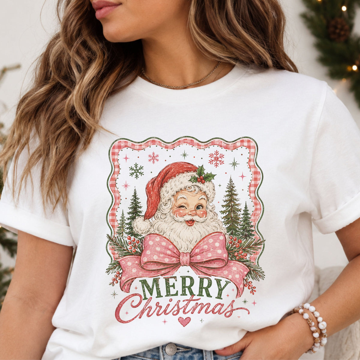 “Merry Christmas” beneath a winking Santa in a red hat, with a pink polka dot bow, evergreen trees and berry branches inside a distressed pink gingham frame.