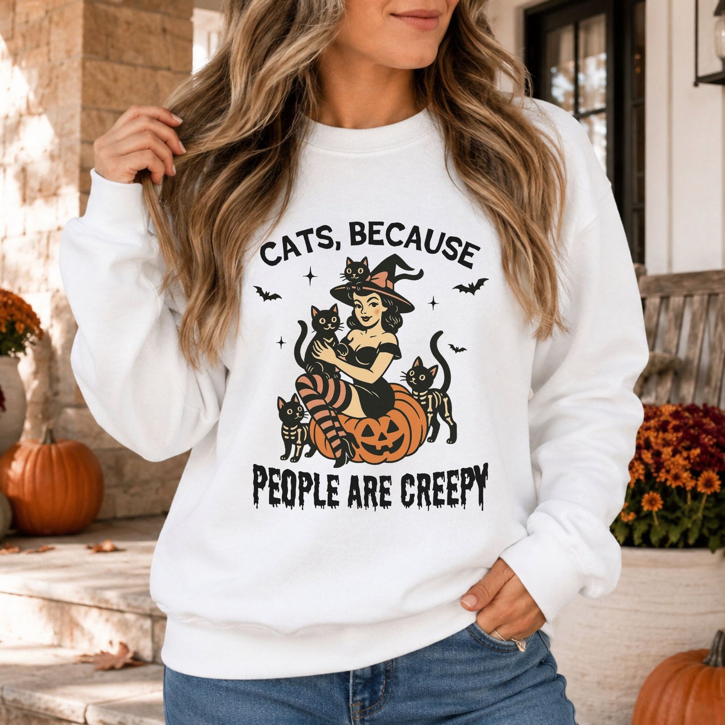 Cats Because People Are Creepy Halloween DTF transfer featuring a retro pinup witch sitting on a smiling jack-o’-lantern surrounded by black cats, skeleton cats, flying bats and sparkling accents on a white sweatshirt mockup.