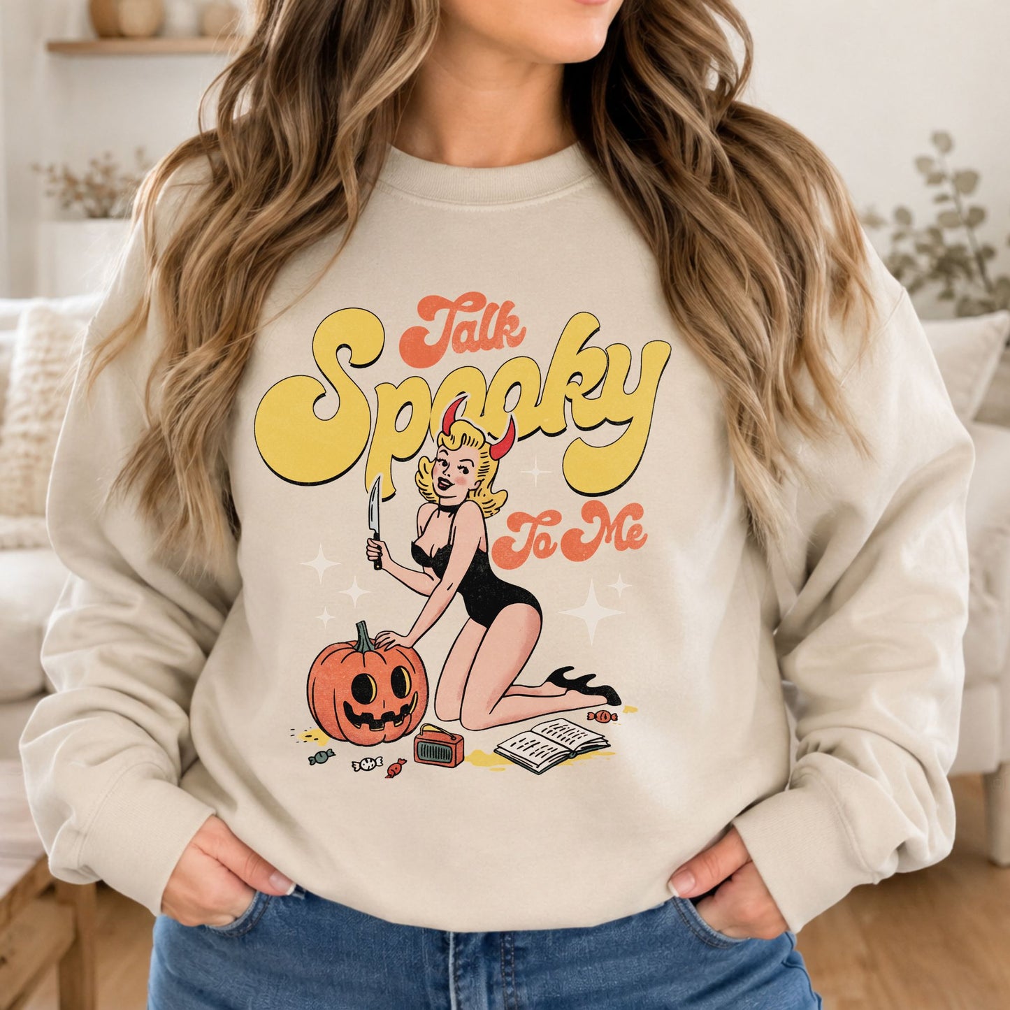 Cream sweatshirt mockup featuring a retro pinup girl with devil horns, a pumpkin, and the phrase Talk Spooky to Me in a vintage Halloween design.