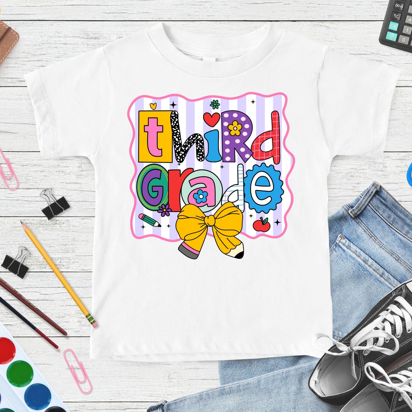 Colorful Third Grade back-to-school design featuring playful patterned letters, a yellow pencil bow, apple, flowers, pencil accents, and pastel striped classroom background.