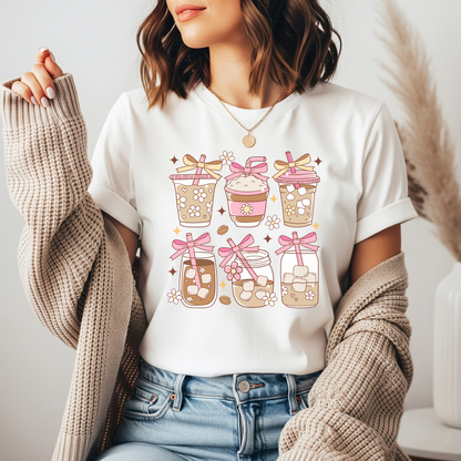 Person wearing a white t-shirt with a graphic design of coffee cups and bows.