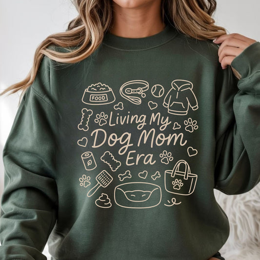 Living My Dog Mom Era line art design featuring dog mom essentials including food bowl, leash, dog bed, paw prints, bones, hoodie, tote bag, and pet accessories in brown outline style