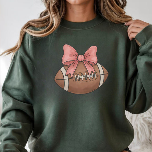 Coquette football graphic featuring a brown football topped with a pink bow in a feminine sports design