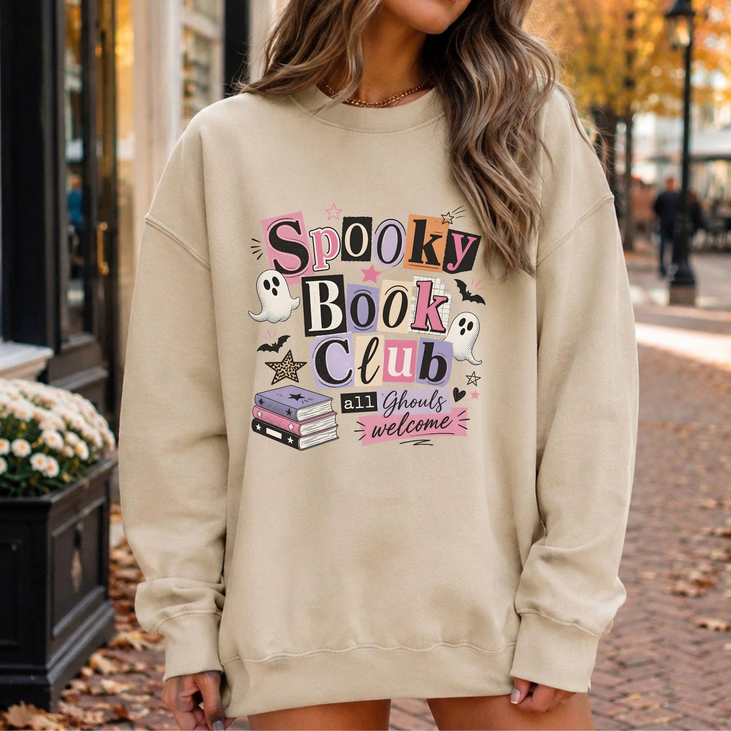 Spooky Book Club All Ghouls Welcome Halloween DTF transfer featuring colorful retro ransom-style lettering, two cute white ghosts, flying bats, stacked books, stars, hearts and pink, purple, orange and black accents on a cream sweatshirt mockup.