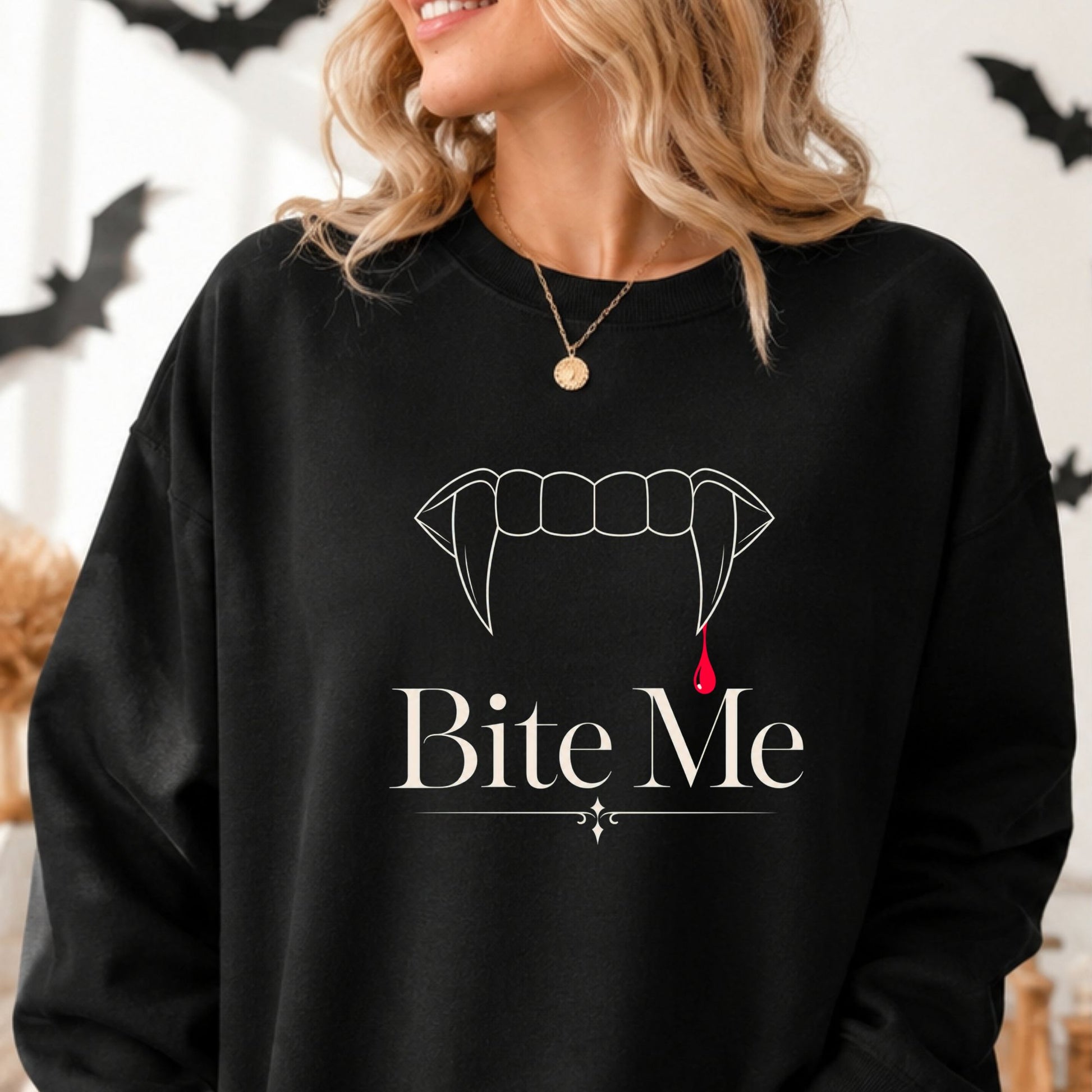 Bite Me Halloween DTF transfer featuring minimalist white vampire fangs with a single red blood drop and elegant gothic lettering, displayed on a black sweatshirt mockup.
