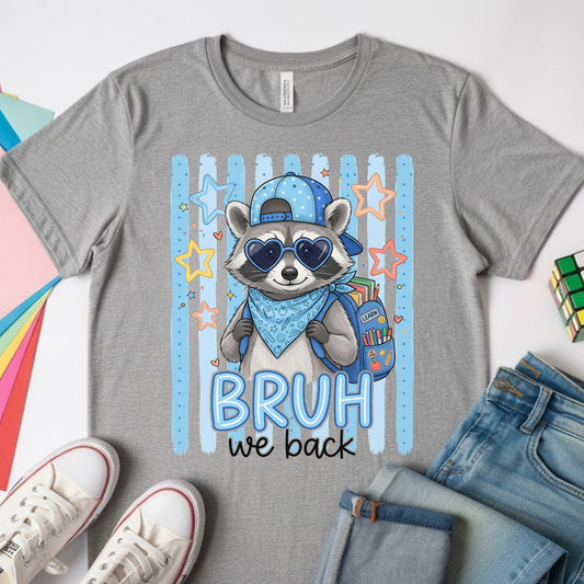 Bruh We Back to School design featuring a cool raccoon wearing heart sunglasses, a blue cap and bandana, and carrying a backpack filled with school supplies.