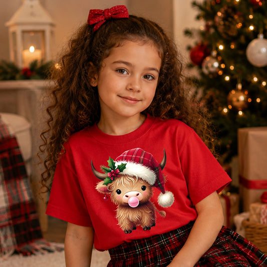 Brown Highland cow blowing pink bubblegum, wearing a red plaid Santa hat with holly and a red bow, plus a red ornament hanging from its ear.
