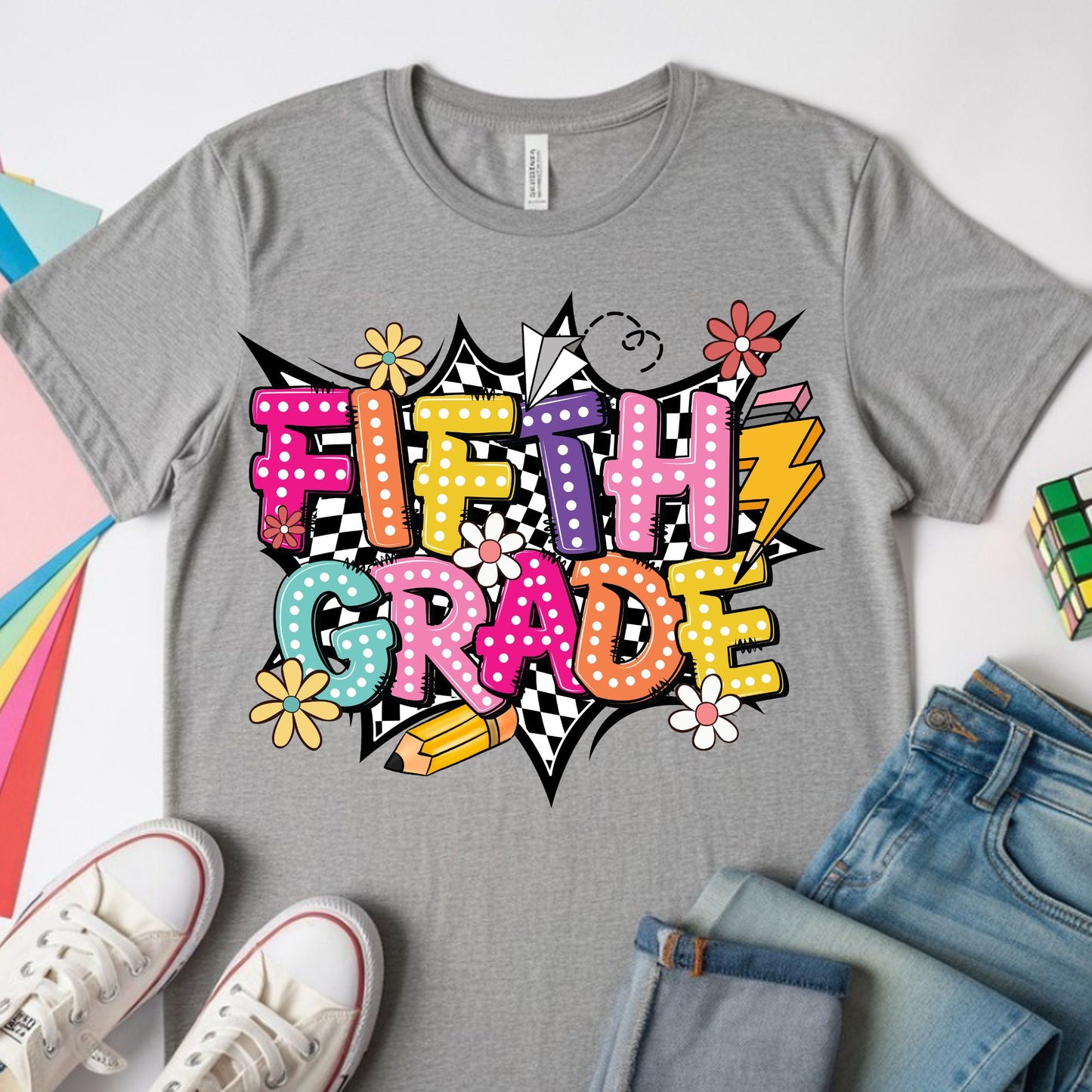 Colorful Fifth Grade back-to-school design featuring bright bubble letters, black-and-white checkerboard accents, flowers, a pencil, paper airplane, lightning bolt, and playful school graphics.