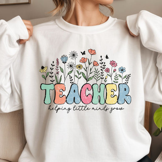 Teacher Helping Little Minds Grow design featuring distressed pastel lettering with colorful wildflowers, leafy stems, butterflies, and a cheerful garden-inspired classroom style.
