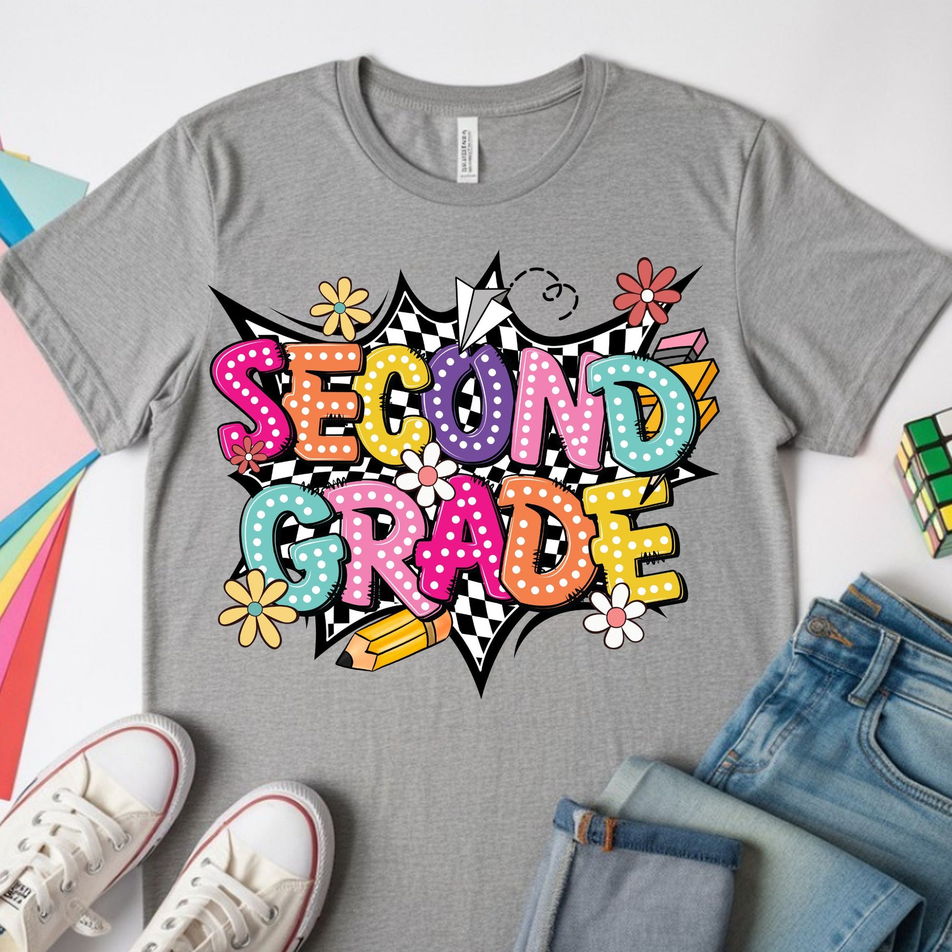 Colorful Second Grade back-to-school design featuring bright bubble letters, black-and-white checkerboard accents, flowers, a pencil, paper airplane, lightning bolt, and playful school graphics.