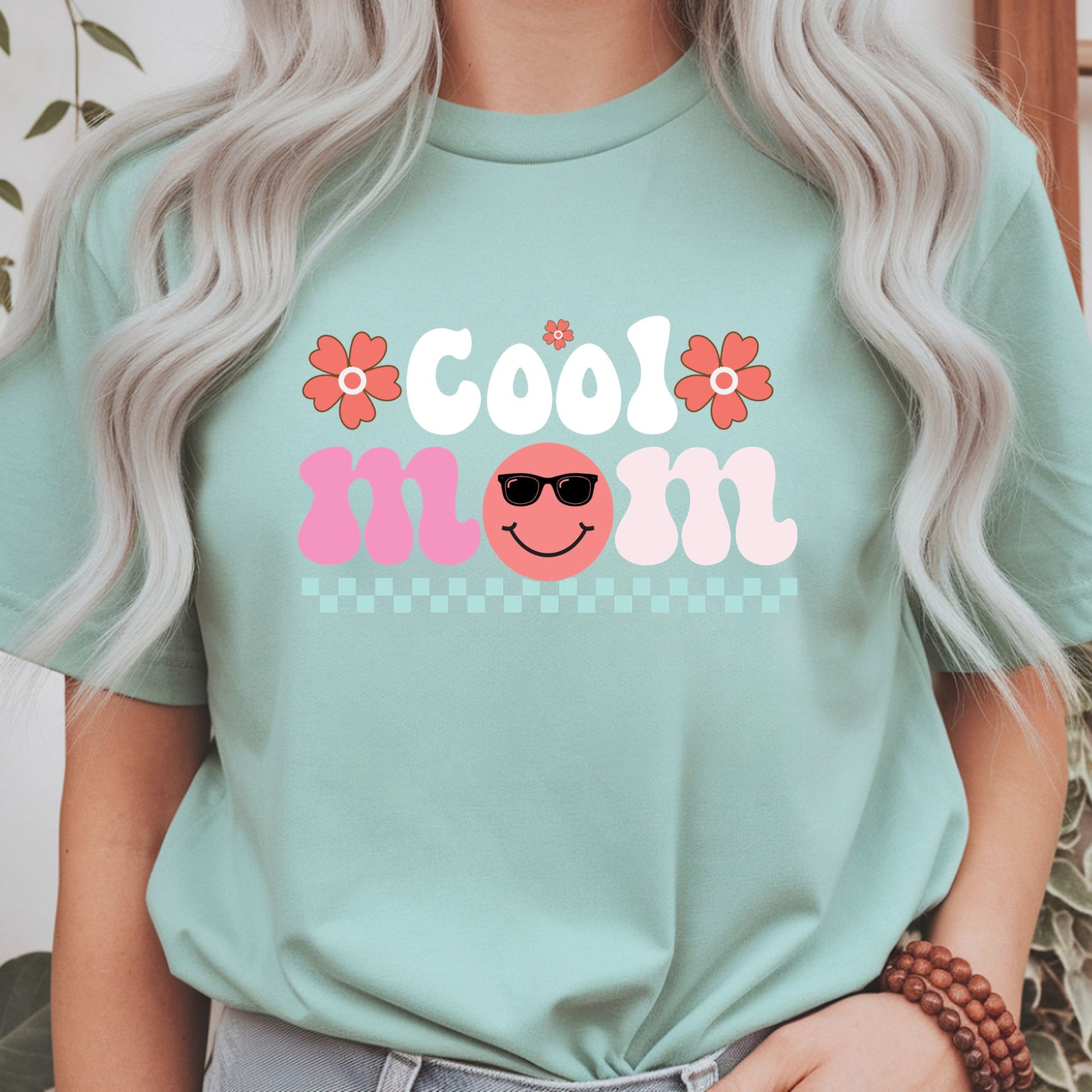 Retro "Cool Mom" design featuring a smiling face with sunglasses, coral flowers, and a pastel checkerboard accent. Perfect for cool moms, trendy moms, Mother's Day gifts, retro lovers, and cute aesthetic graphic tees and hoodies.
