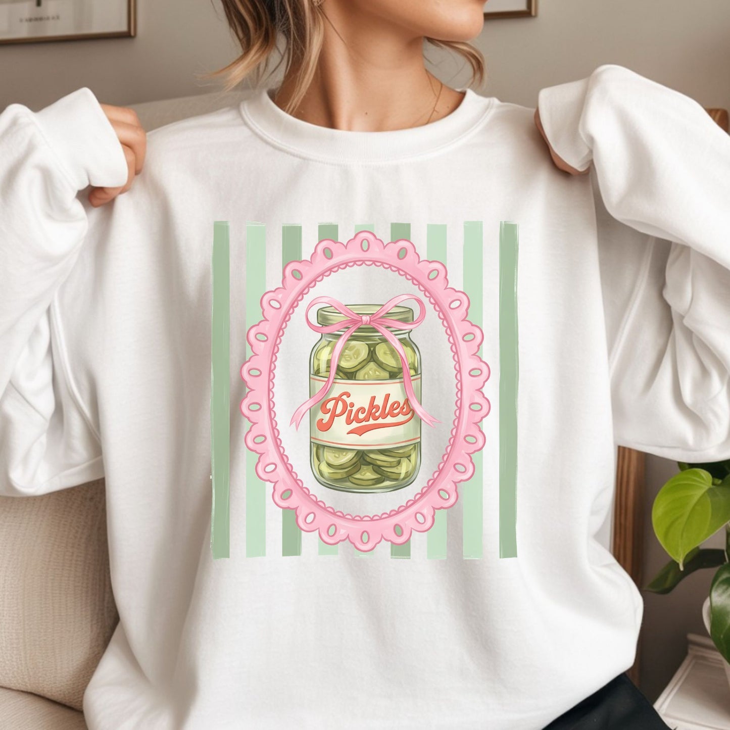 Cute coquette pickle jar graphic featuring a vintage pickle jar, pink bow, scalloped frame, and green striped background for trendy graphic tees, hoodies, and preppy apparel.
