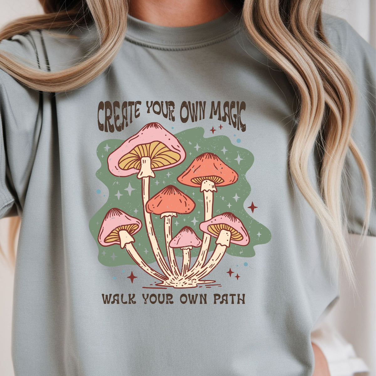Whimsical pastel mushroom design with the inspirational quote "Create Your Own Magic, Walk Your Own Path." Perfect for cottagecore, boho, nature lovers, forest aesthetic, and whimsical graphic tees and hoodies.
