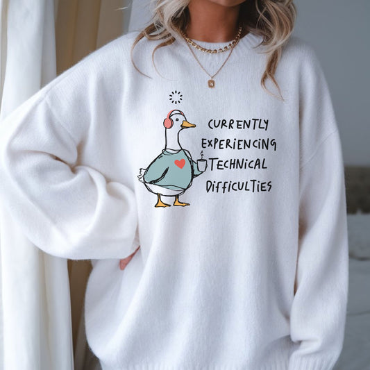 Currently Experiencing Technical Difficulties goose DTF transfer featuring a funny white goose wearing pink headphones, holding a coffee mug, and wearing a blue sweatshirt with a heart for sarcastic shirts, funny goose sweatshirts, tote bags, and quirky graphic apparel.