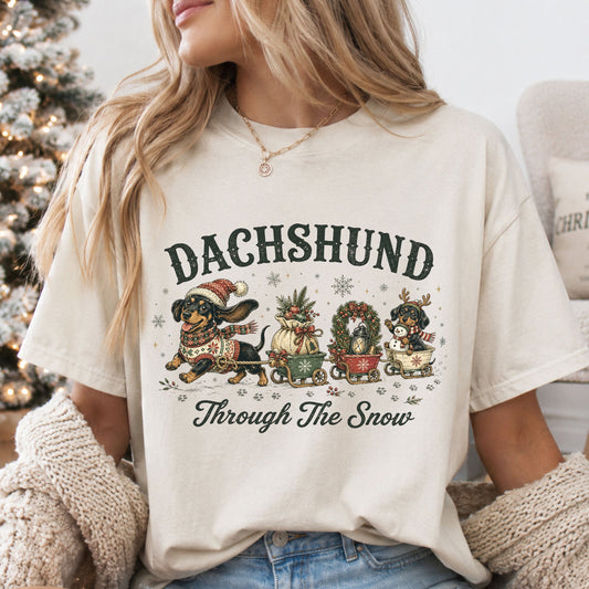 Dachshund Through the Snow vintage Christmas design with a dachshund pulling three wagons carrying ornaments, a wreath, lantern and a puppy holding a snowman.