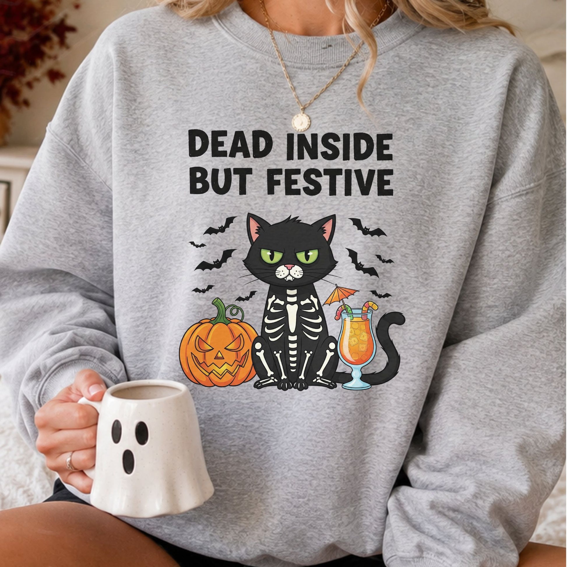 Dead Inside but Festive Halloween DTF transfer featuring a grumpy black cat wearing a skeleton costume beside a jack-o-lantern and orange cocktail, surrounded by flying bats on a gray sweatshirt mockup.