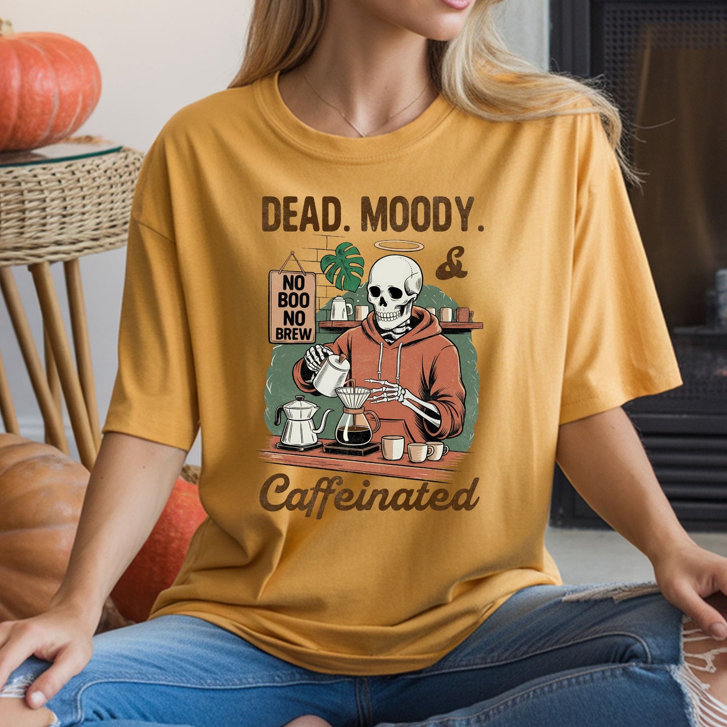Dead, Moody and Caffeinated Halloween DTF transfer featuring a haloed skeleton barista making pour-over coffee with mugs, a moka pot and a No Boo No Brew sign on a mustard yellow T-shirt mockup.