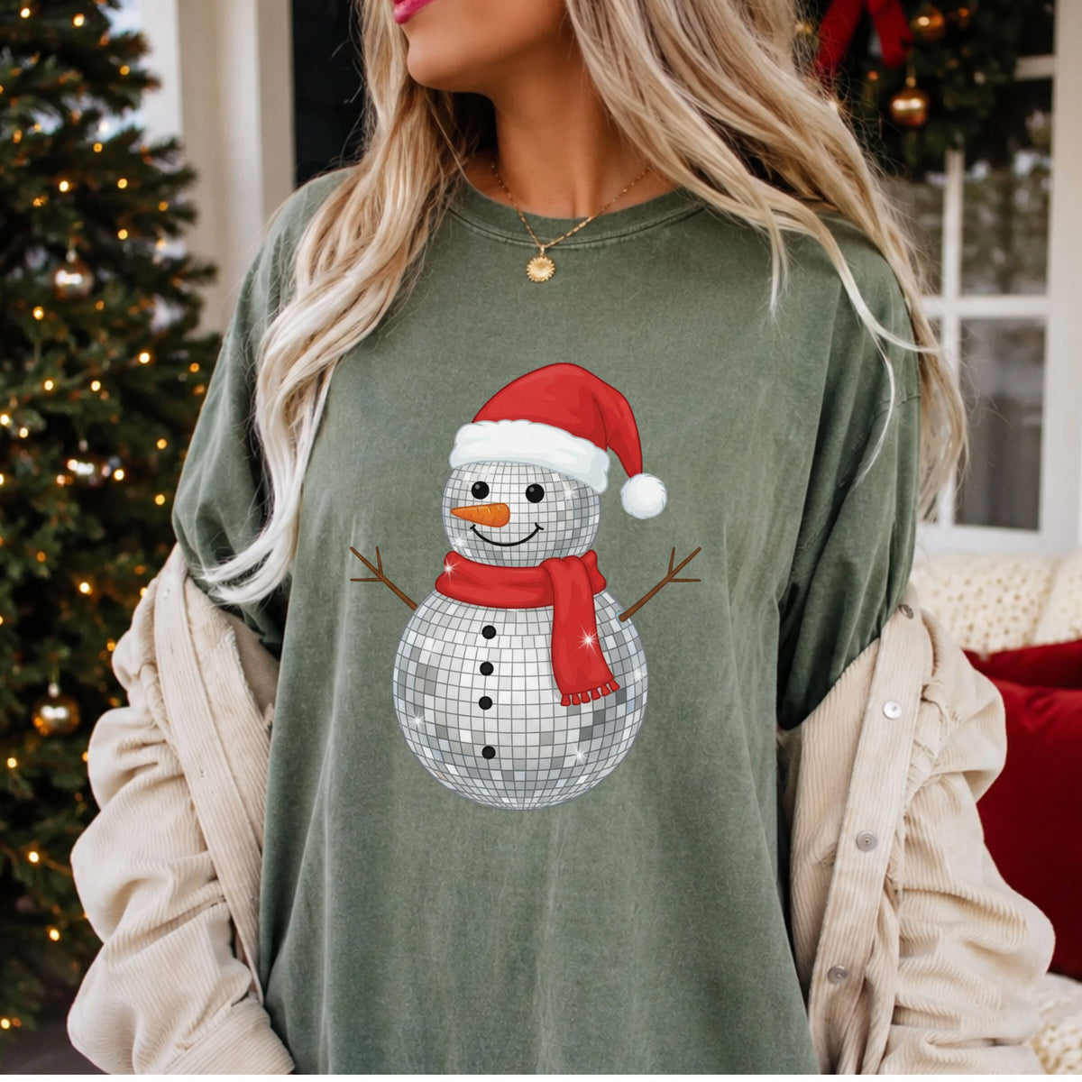 Smiling silver disco ball snowman wearing a red Santa hat and scarf, with a carrot nose, black buttons, twig arms and illustrated sparkle accents.