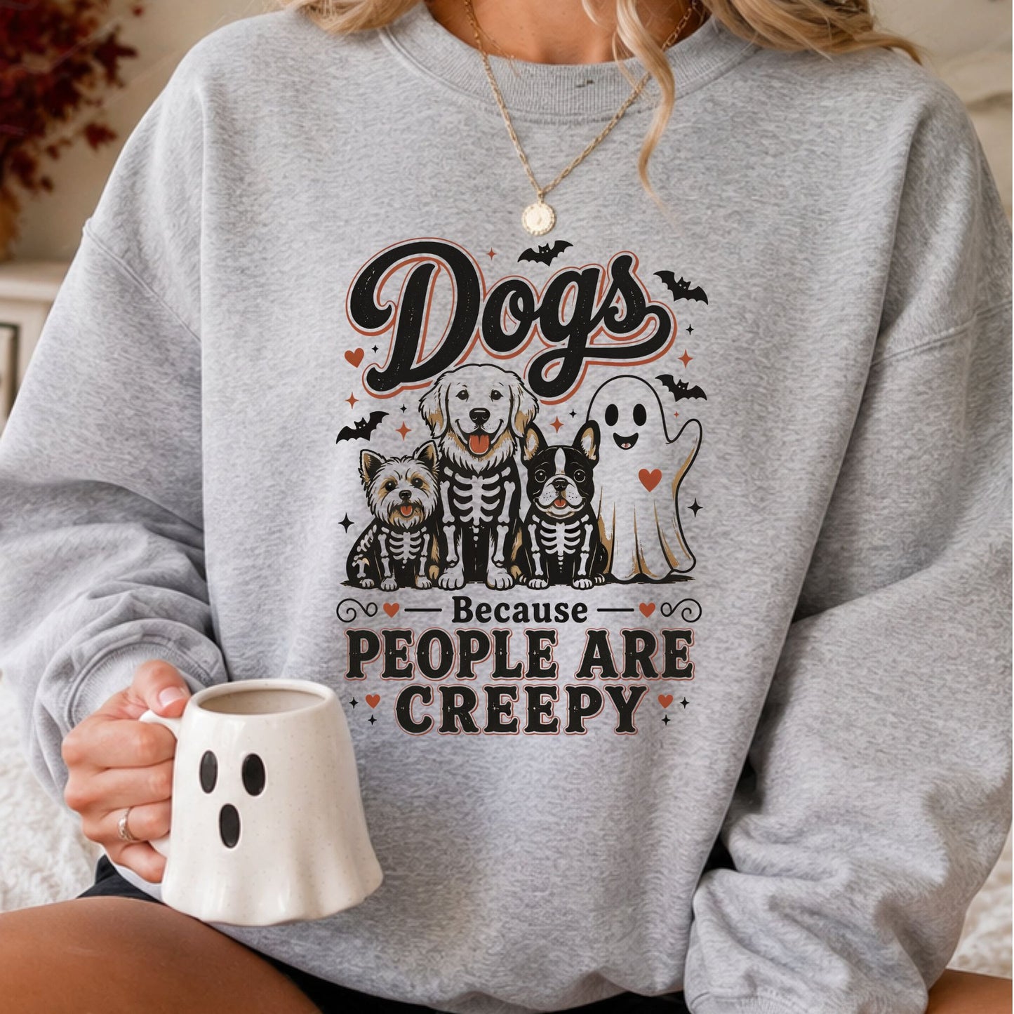 Dogs Because People Are Creepy Halloween DTF transfer featuring three adorable dogs wearing skeleton costumes beside a smiling sheet ghost, surrounded by black bats, orange hearts and spooky accents on a gray sweatshirt mockup.