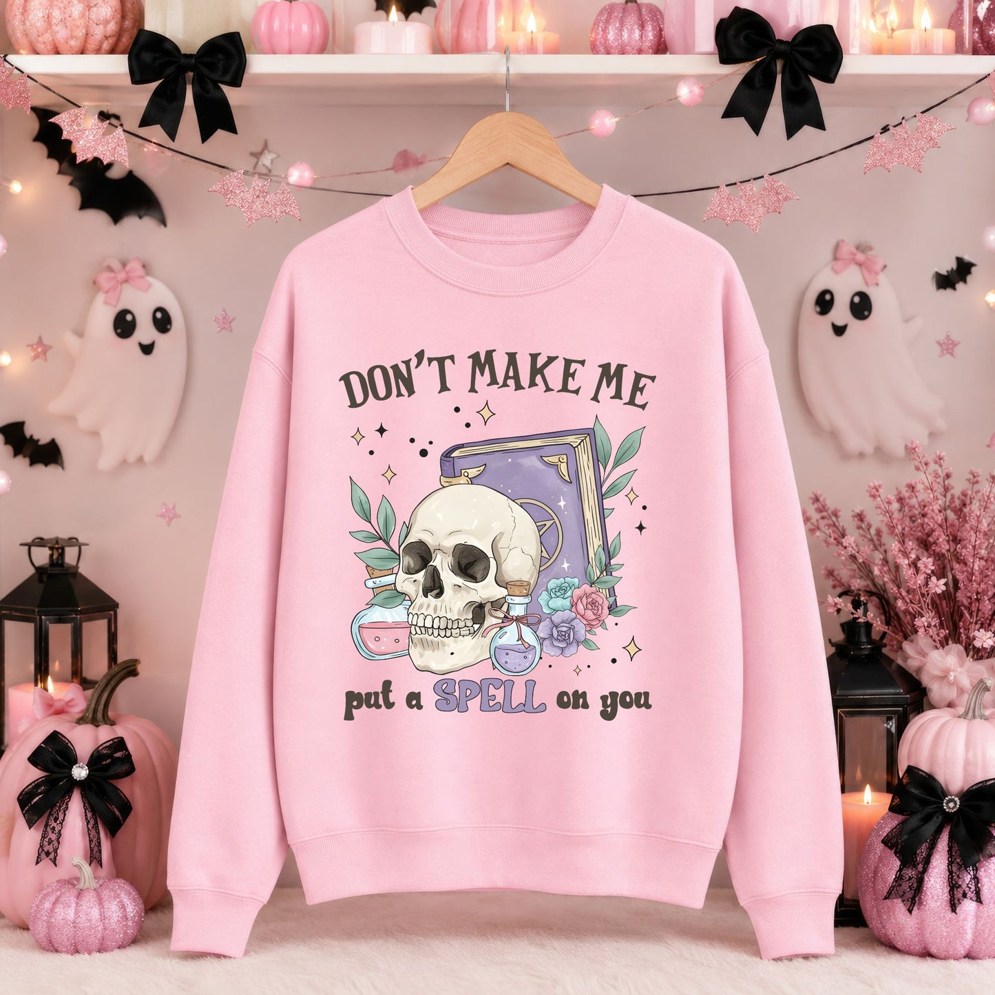 Don’t Make Me Put a Spell on You Halloween DTF transfer featuring a detailed skull, purple spell book, colorful potion bottles, pastel flowers, green leaves and sparkling magical accents on a pink sweatshirt mockup.