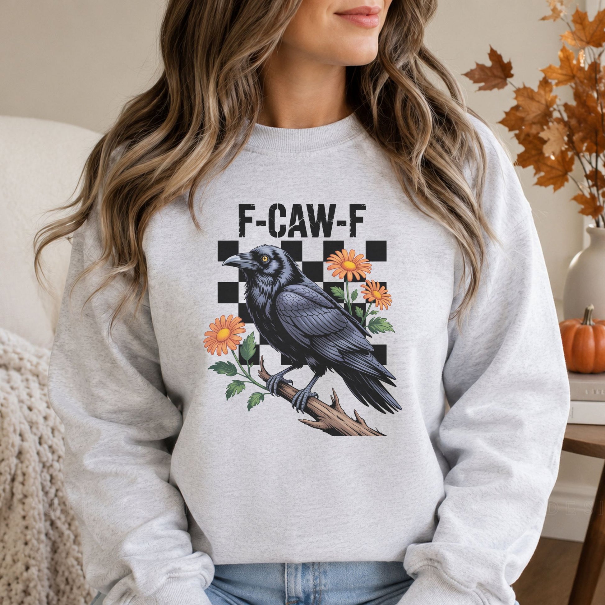 Funny F-Caw-F Halloween DTF transfer featuring a detailed black raven perched on a branch with orange flowers and a bold black checkerboard background, displayed on a gray sweatshirt mockup.
