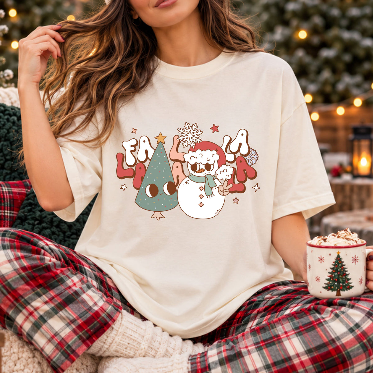 “Fa La La La La” in white, peach and coral bubble letters behind a smiling sage Christmas tree and a snowman wearing a red Santa hat and green scarf, making a peace sign.