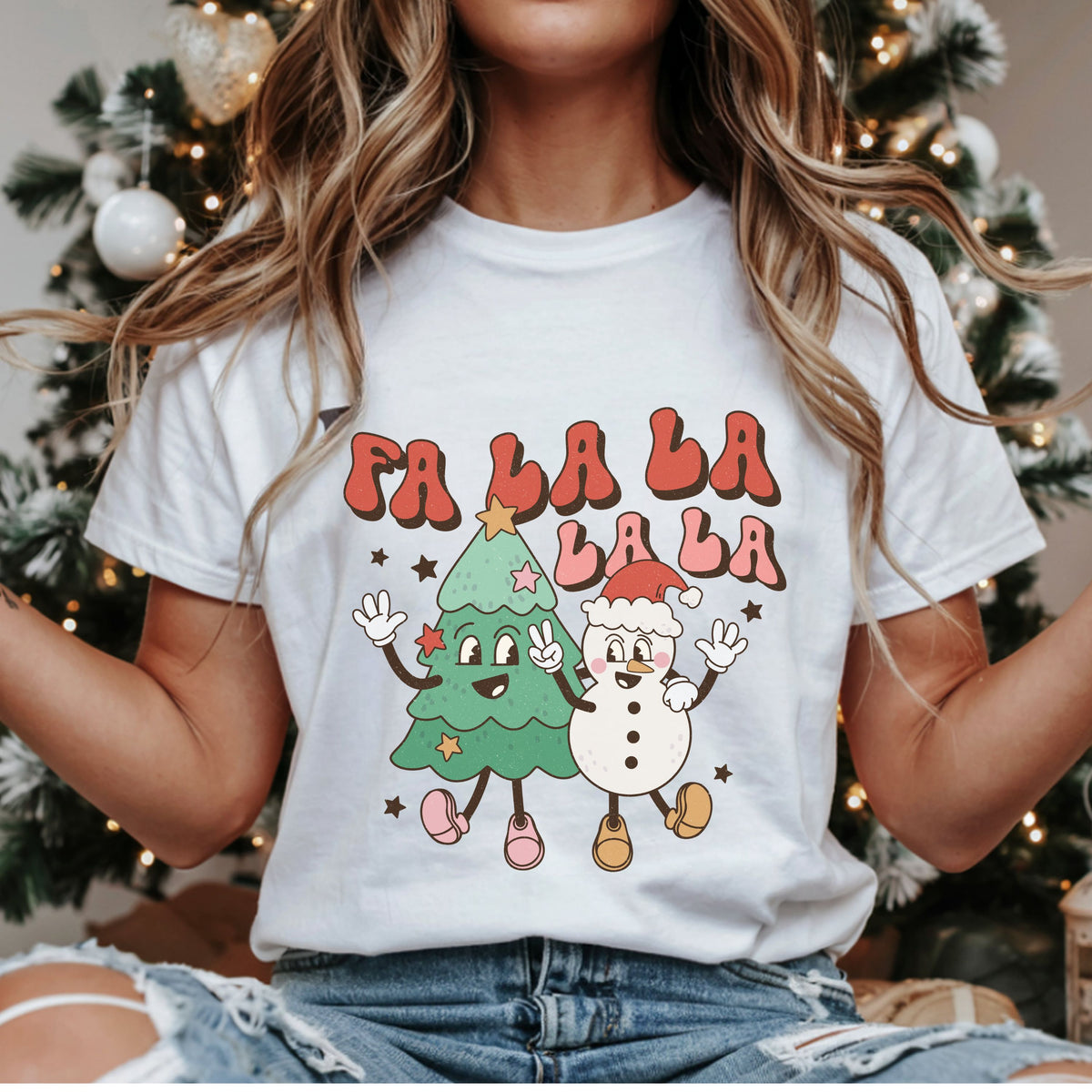 “Fa La La La La” in red and pink bubble letters above a smiling Christmas tree and snowman in a Santa hat, with waving hands, a peace sign and stars.