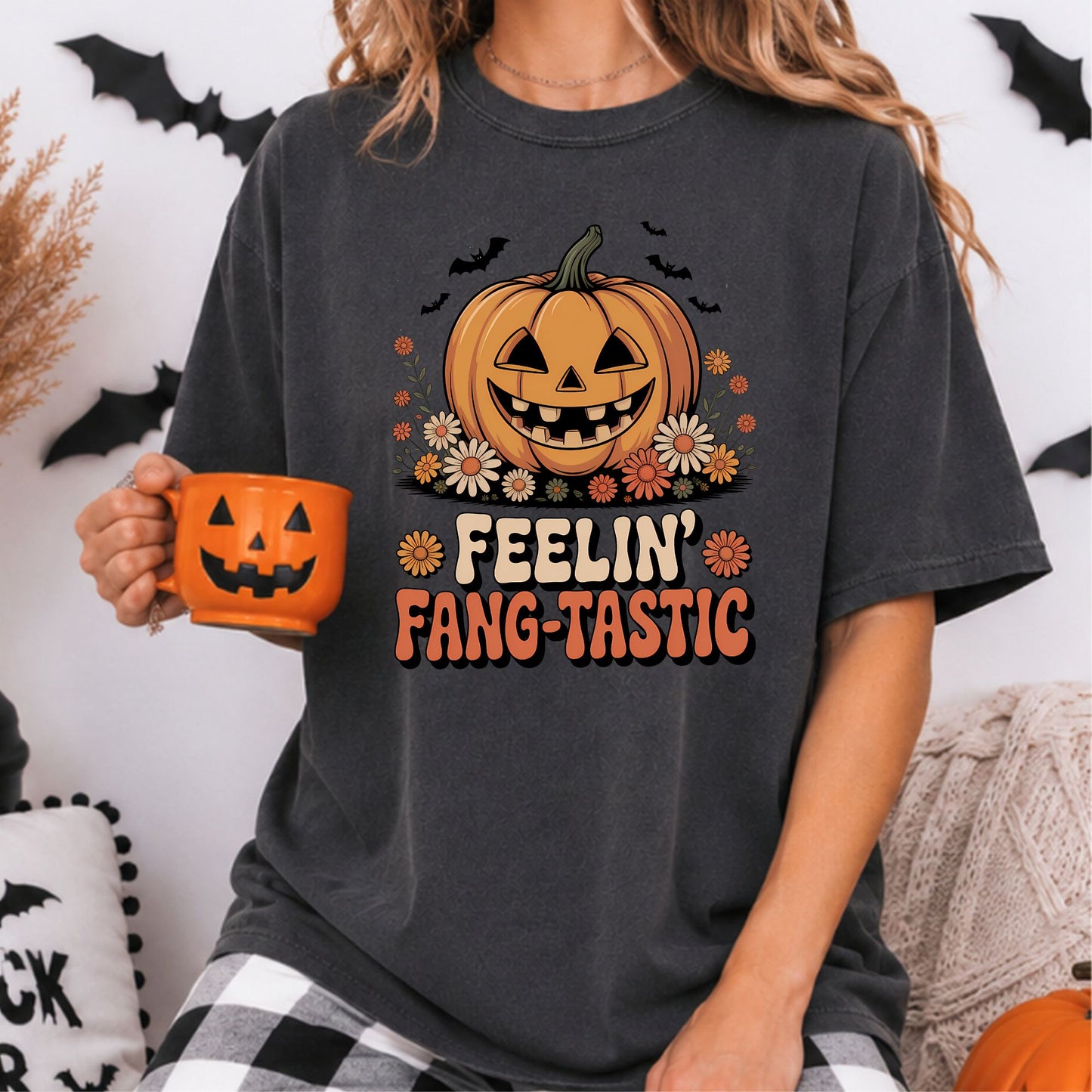 Feelin’ Fang-Tastic Halloween DTF transfer featuring a smiling jack-o-lantern surrounded by retro orange flowers, black bats and groovy cream and orange lettering on a dark gray T-shirt mockup.