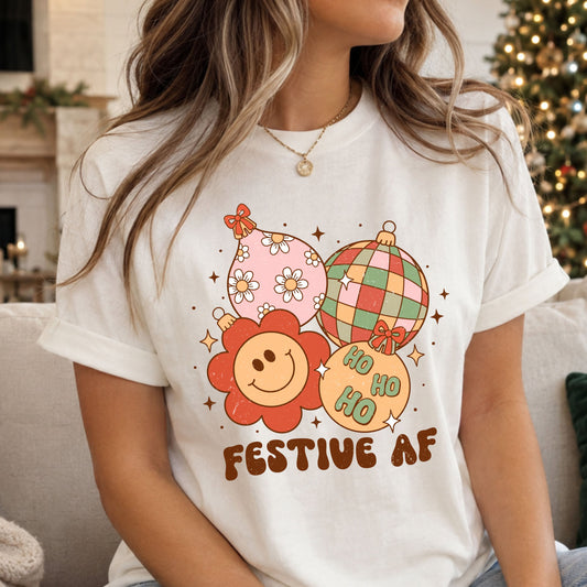 Festive AF beneath four Christmas ornaments: a pink floral teardrop, colorful disco ball, coral smiley flower and peach Ho Ho Ho bauble, surrounded by bows and starbursts.