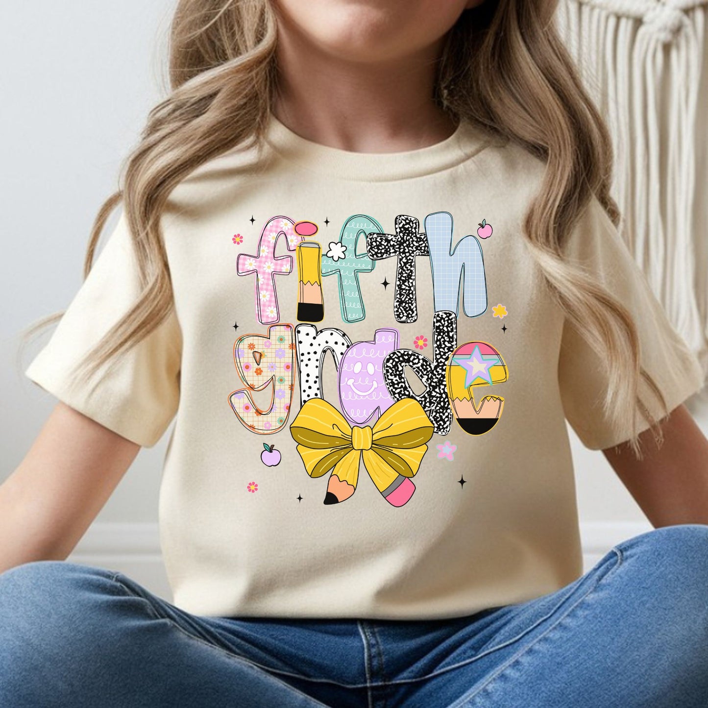 Fifth Grade back-to-school design featuring colorful patterned letters, a pencil detail, yellow pencil bow, flowers, apples, and playful classroom accents for kids shirts.
