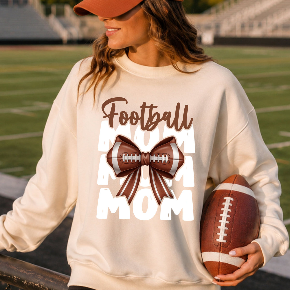 Football Mom DTF transfer featuring bold white stacked MOM lettering, brown Football script, and an oversized realistic football-shaped bow with laces and striped ribbon tails.