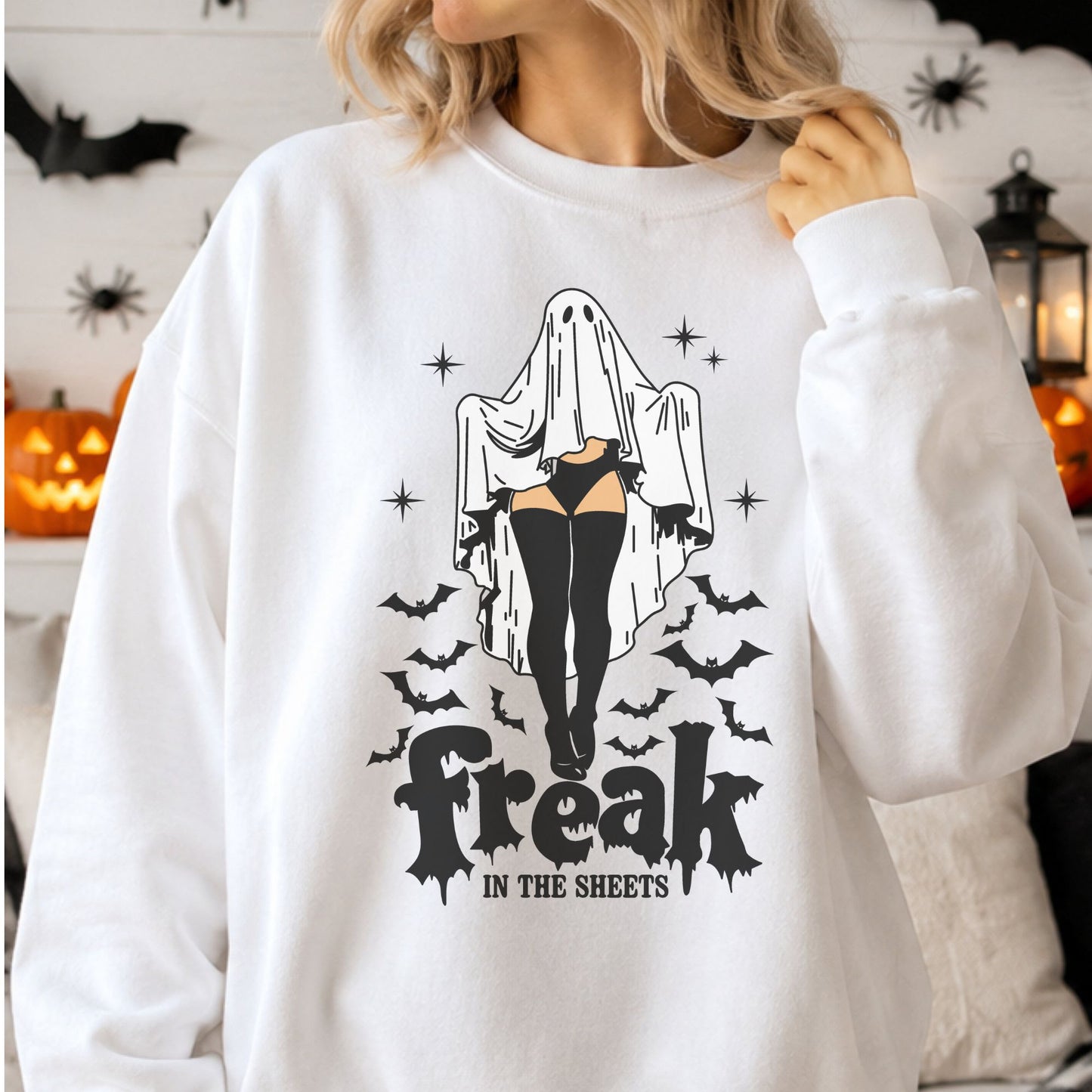 Freak in the Sheets Halloween DTF transfer featuring a sexy sheet ghost wearing black lingerie, thigh-high stockings and gloves, surrounded by flying bats and sparkling stars on a white sweatshirt mockup.