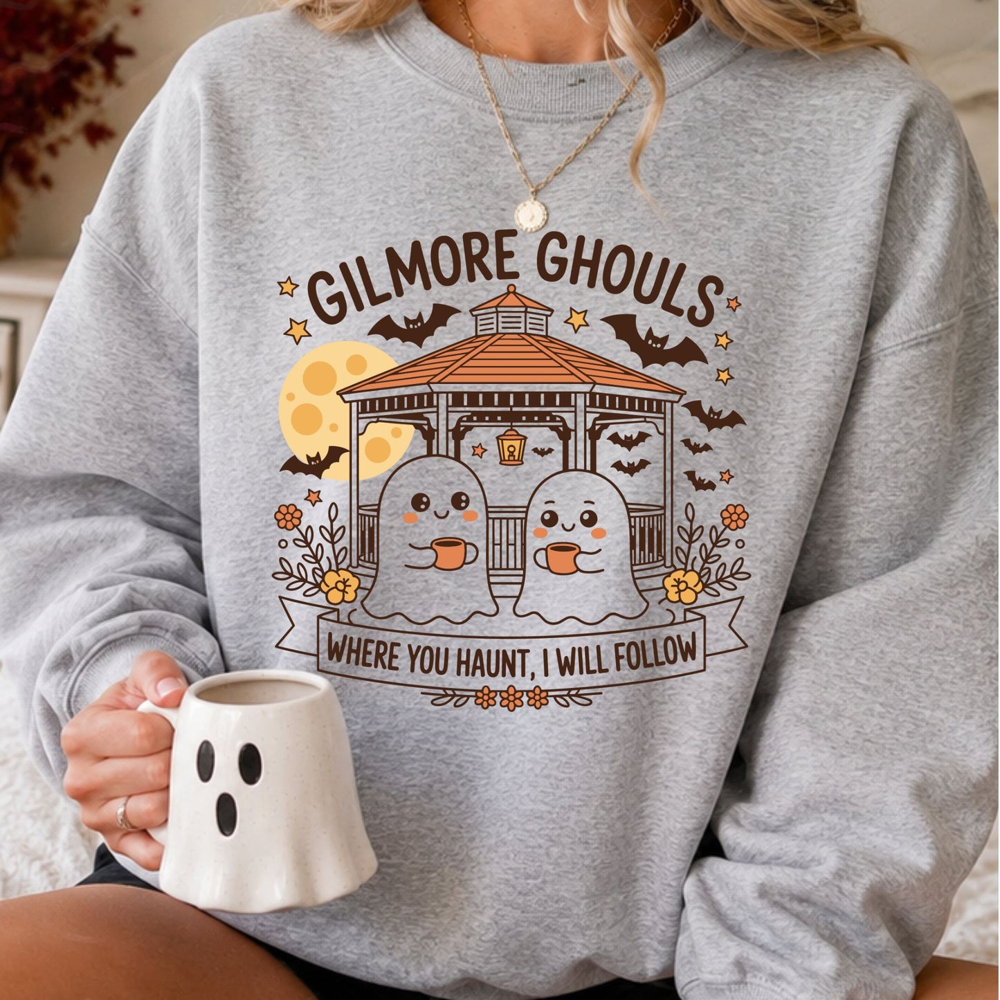 Gilmore Ghouls Halloween DTF transfer featuring two cute ghosts holding coffee mugs beneath a gazebo, full moon and flying bats with the phrase Where You Haunt, I Will Follow on a gray sweatshirt mockup.