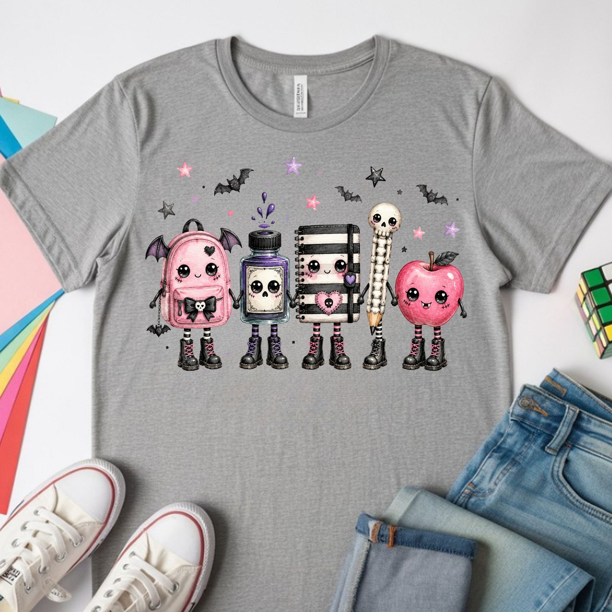 Gothic kawaii back-to-school design featuring a pink bat-wing backpack, ink bottle, composition notebook, skeleton pencil, apple, bats, stars, and cute spooky school characters.