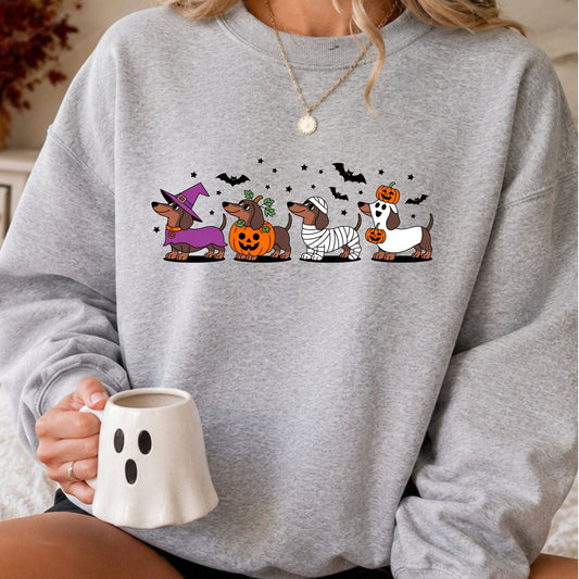 Dachshund Halloween DTF transfer featuring four cute wiener dogs dressed as a witch, pumpkin, mummy and ghost with bats and stars