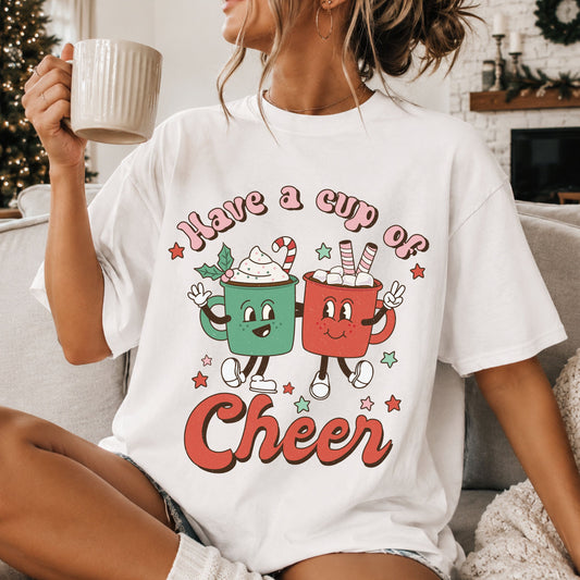 “Have a Cup of Cheer” with smiling green and red hot cocoa mugs, whipped cream, marshmallows, a candy cane and stars in a distressed retro style.