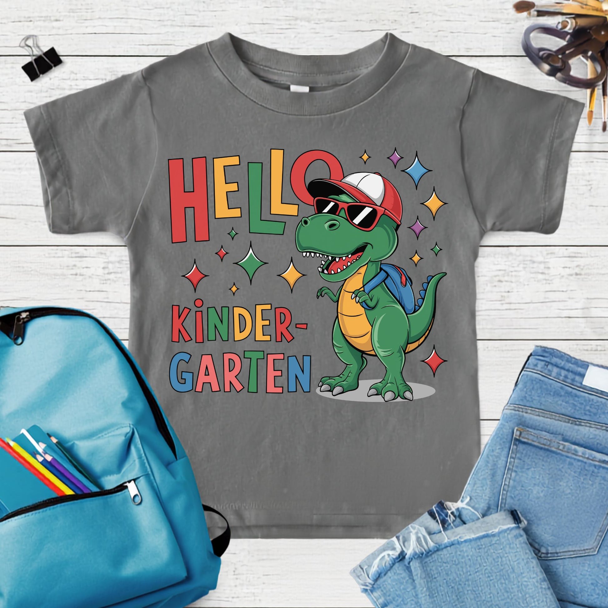 Hello Kindergarten back-to-school design featuring a green dinosaur wearing sunglasses, a red cap, and a blue backpack with colorful sparkles and bold lettering.