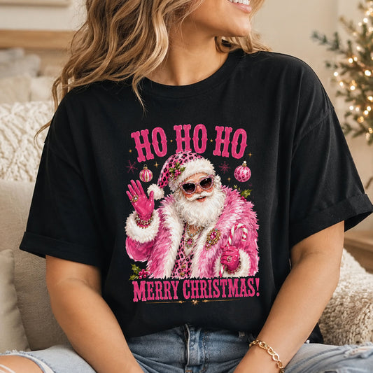 “Ho Ho Ho” and “Merry Christmas!” surround Santa in a fluffy pink coat, jeweled cat-eye sunglasses and pink gloves, waving and holding a candy cane.